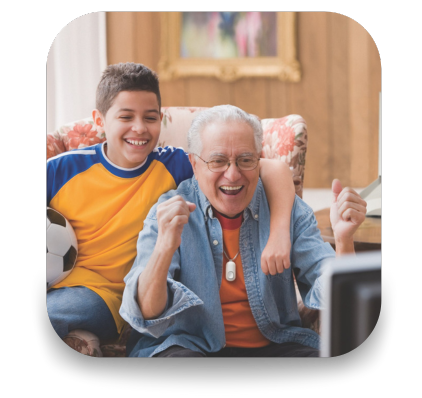 Older Man with grandchild watching soccer together cheering. While wearing a Lifeline Button.