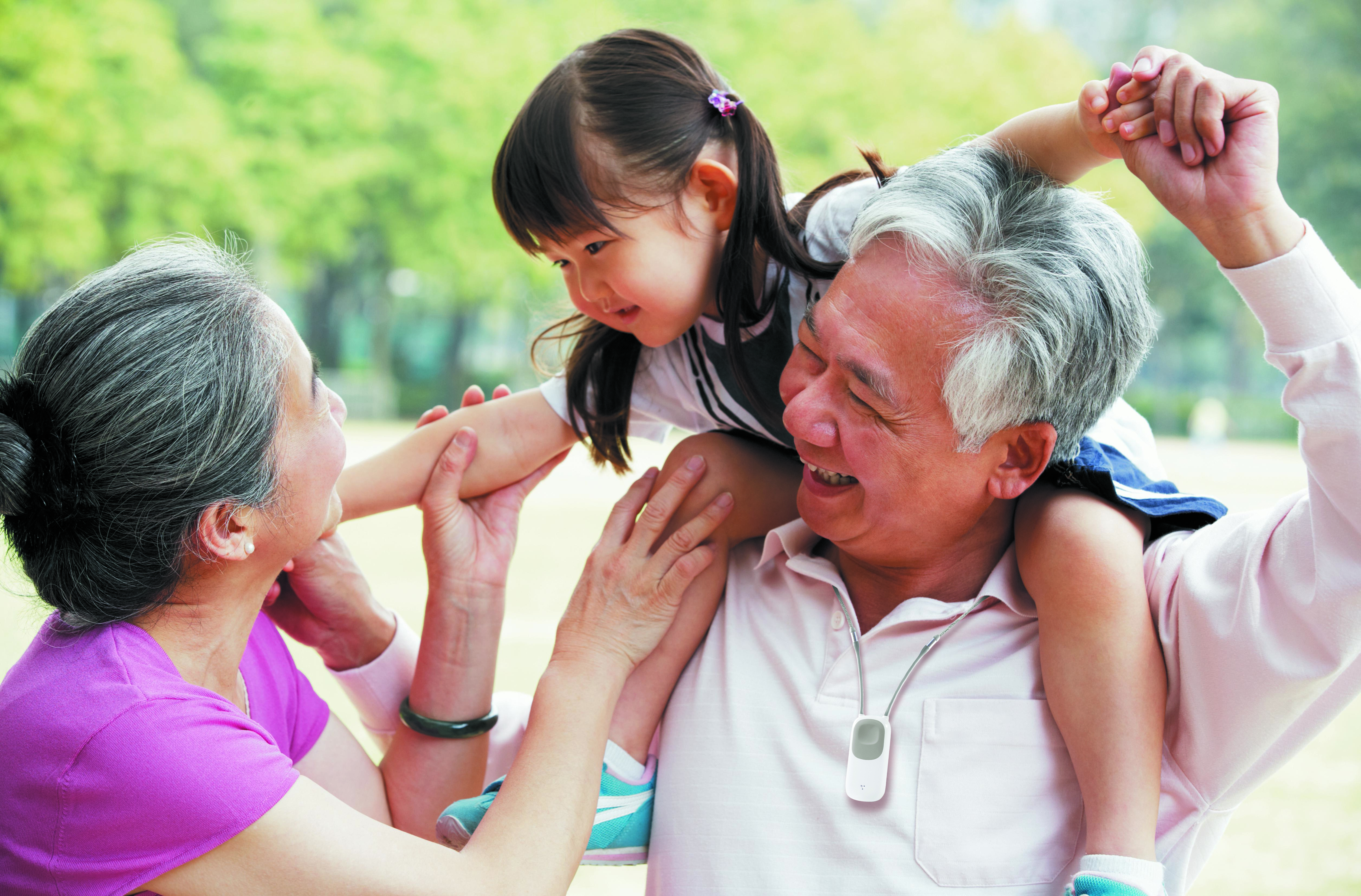 Asian Grandfather wearing a Go Safe mobile button with his wife by his side and his granddaughter sitting on his shoulders.