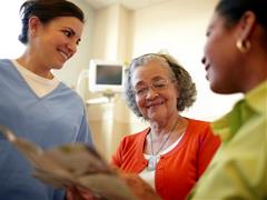 Older black woman and her daughter talking with a nurse in a hospital setting.